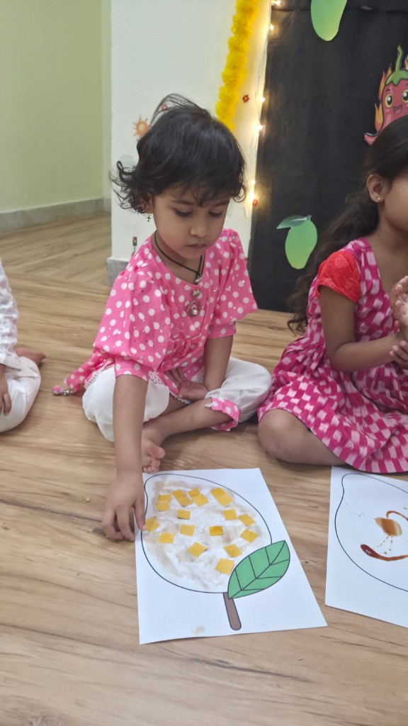 Child decorating a mango craft with yellow paper squares